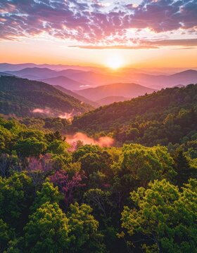 Sunrise over a misty mountain range with lush green forests.