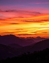 Fototapeta premium Majestic mountain range silhouetted against a vibrant sunset sky.