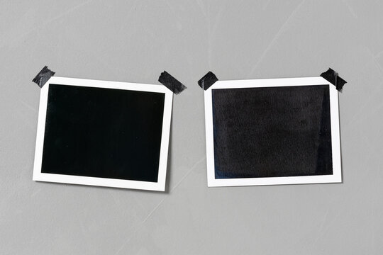 two blank photo print taped to a textured grey wall with black adhesive tape
