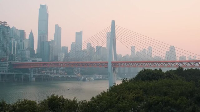 Modern bridge spanning Yangtze River with skyline of Chongqing city, China, at sunset. Urban travel, transportation networks, contemporary architecture, business centers, waterfront development