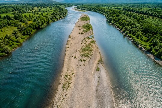 Sandbar in a river with parallel water flows, aerial view of natural landscape.