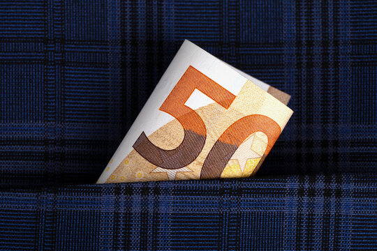 Close-up of a folded 50 euro banknote emerging from the pocket of a blue plaid fabric, symbolizing savings, finance, or budgeting.