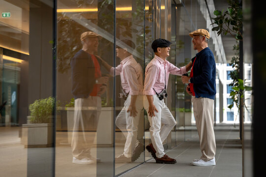 Happy Senior Asian Men Chatting Stylishly by Glass Wall Reflection, City Lifestyle