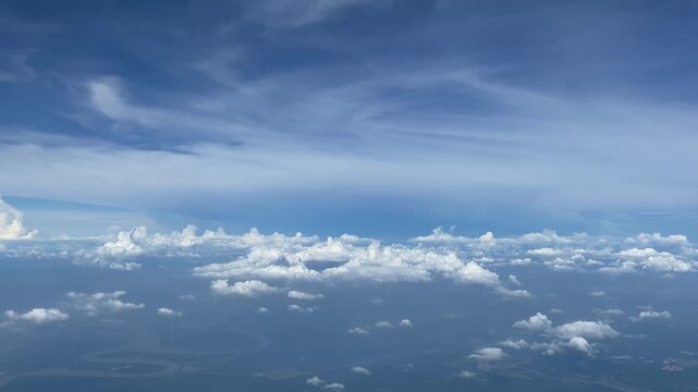 High-altitude aerial view of layered cumulus and stratus clouds over a landscape with winding rivers and lakes in Sri Lanka, captured during daytime.