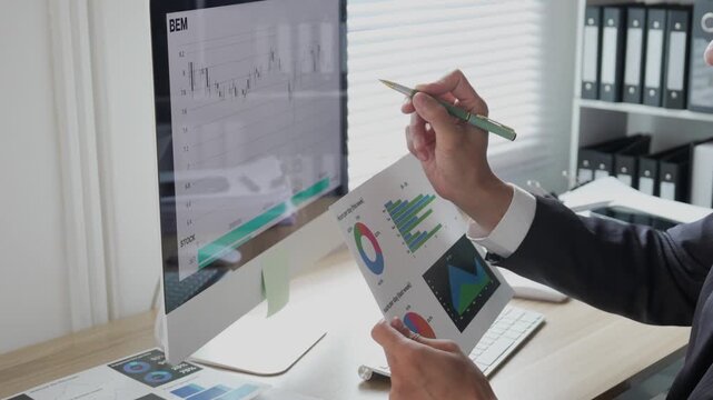 A young professional is examining investment data graphs and charts, analyzing financial information, and monitoring stock market trading reports.