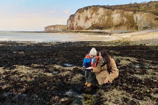 mother and son walking on the seabed after low tide