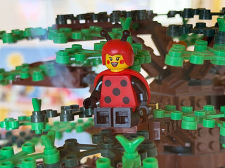 Obraz premium Toy ladybug figure sitting in a lego style tree with green leaves, playful kids building scene.