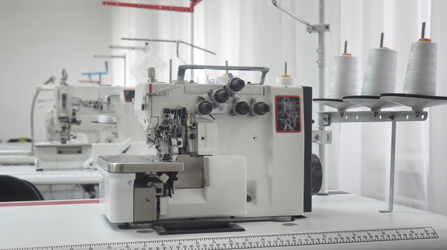 Industrial overlock sewing machine with white thread spools in workshop