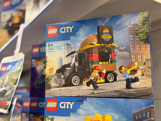 Obraz premium Lego city toy box displayed on a retail shelf in a store, showing a delivery truck playset and colorful packaging.