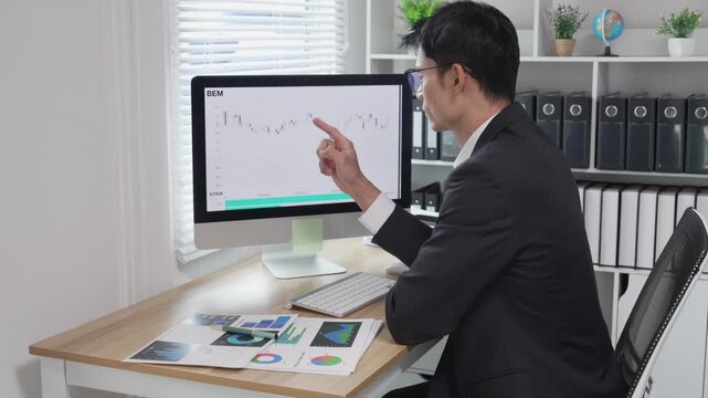 A stressed Asian businessperson holds documents and looks anxious about errors in a financial report amidst a stock market slump or financial losses.