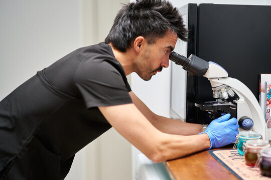 Veterinary professional examining samples using a microscope in lab