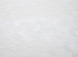 Obraz premium Close-up of pristine white quilted fabric surface, showcasing soft textile texture and intricate stitching pattern for comfort and bedding aesthetics