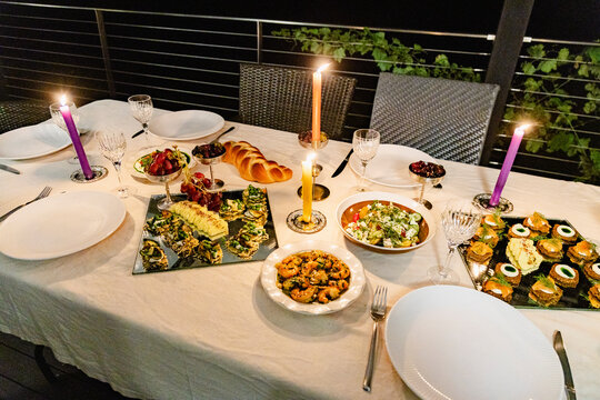 Candlelit outdoor dinner table with seafood and challah bread