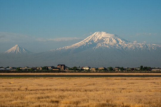 YEREVAN, ARMENIA - JUNE 7, 2026: Scenic panoramic view of the majestic snow-capped Mount Ararat and Little Ararat rising above rural houses, captured from Zvartnots International Airport.