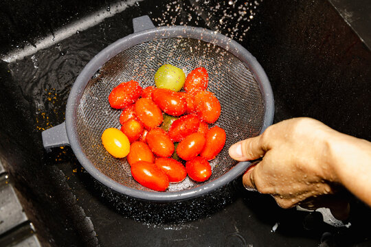 Rinsing cherry tomatoes in sink for healthy dinner prep