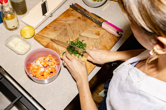 Chef chopping herbs beside prawns for catered seafood dinner