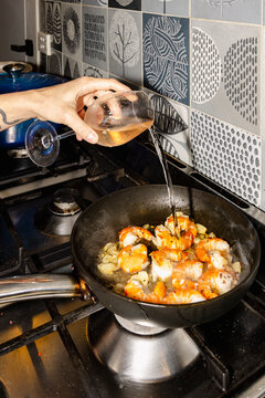 Pouring wine over prawns while cooking seafood at home