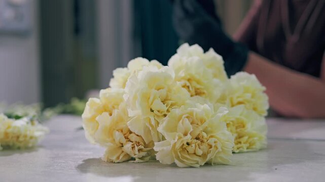 Young florist making bouquet of roses and dried flowers at workplace. Floral artist working in flower shop studio. Floristry showing masterclass on creating flower arrangement. Small woman business.
