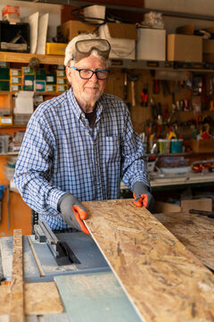 Elderly Man Working in a Garage Filled With Tools and Wood