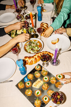 Hands reaching for shared dishes at dinner party