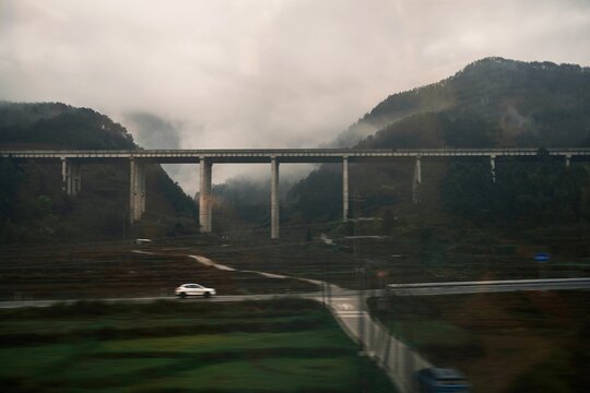 Bridge spans across valley with fog and mountain backdrop