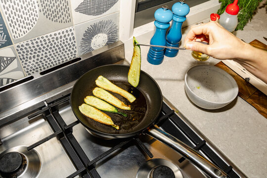 Chef turning zucchini in pan for healthy catered dinner with flash