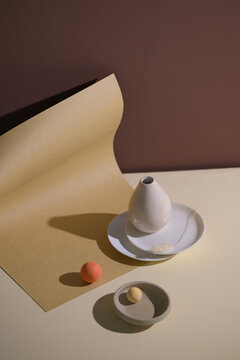 Minimalist still life composition with a white vase, plates, and balls