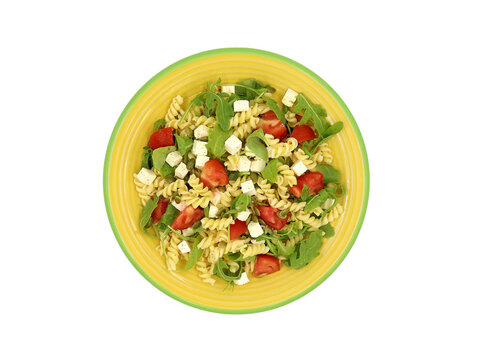 A delicious summer dish: spiral pasta, tomato, arugula, feta cheese cubes, and roasted pumpkin seeds. Top view.