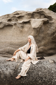Elegant Woman Sitting On Rocks