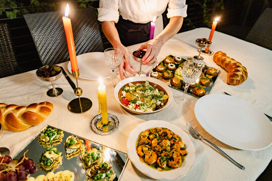 Hands placing fruit bowls on candlelit catered dinner table