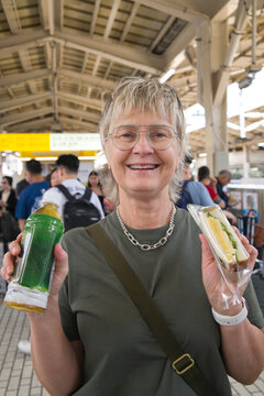 Tourist at Train Station Holding Green Tea and Egg Sandwich Snack