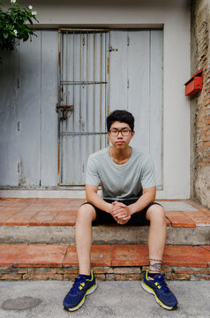 Teenager sitting in front of a classic building in Thailand