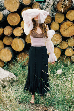 Woman posing in fashion tulle top against log pile