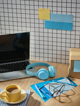 Desk setup with laptop, headphones, coffee, and study materials