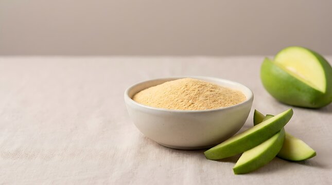 Bowl of fresh mango powder with sliced green mango fruit pieces on a rustic table surface. mango powder