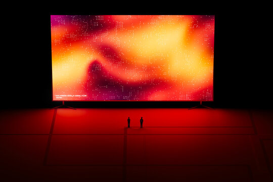 A man and woman stands in front of a large digital screen