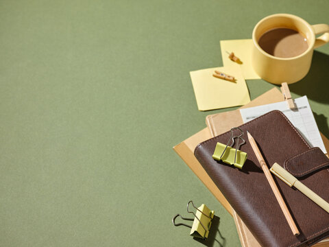 Desk setup with coffee, notebook, and stationery for planning on green
