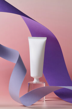Minimalist white cosmetic tube displayed on a clear pedestal
