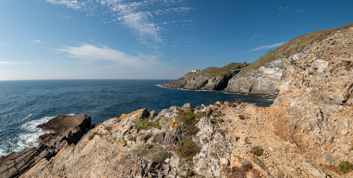 A wide panoramic landscape photograph of the dramatic rocky coastline at Mizen Head, Ireland, showing jagged geological formations, coastal cliffs, and the historic Signal Station visible in the far d