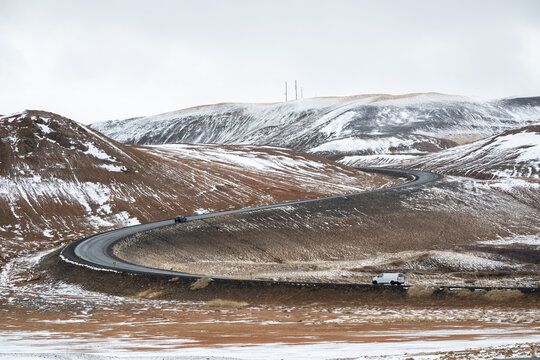 Cars traveling winding ring road through a vast, rugged winter landscape in iceland, namaskardh mountain pass . Iceland