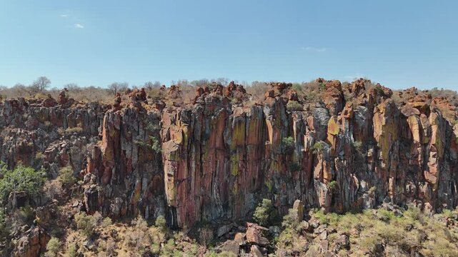 Cinematic aerial footage of majestic red sandstone cliffs and rugged escarpments in the arid wild savanna of Namibia, Africa. Epic geological formations.