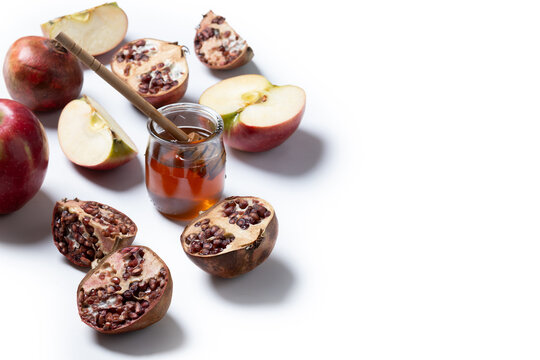 Traditional Rosh Hashanah food with apples, honey and pomegranates on white background