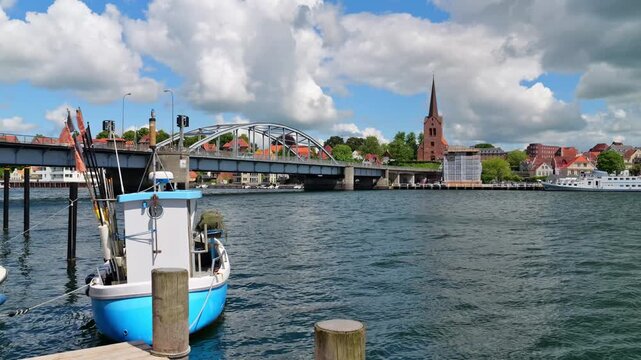 Video showing a fishing boat gently rocking in the wind in front of King Christian X Bridge, Saint Mary Church and the old town of Sonderborg.