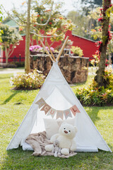 Children's teepee tent with teddy bear in a sunny garden © Marco