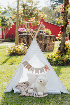 Children's teepee tent with teddy bear in a sunny garden