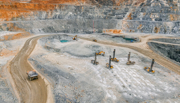 Aerial open pit mine with drilling rigs and haul road for industrial mining background and construction site