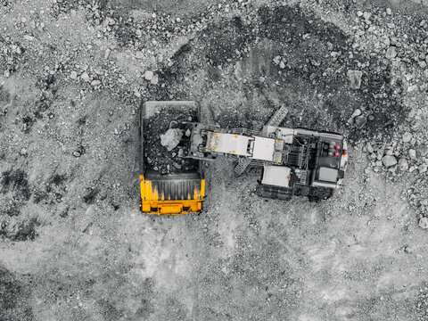 Top down aerial view of excavator loading dump truck in open pit mine for industrial mining