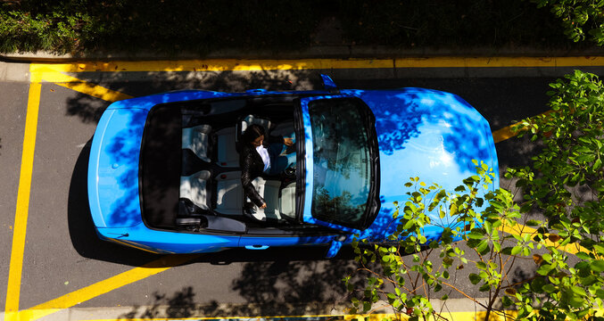 A stylish Asian girl sleeps inside a blue convertible.