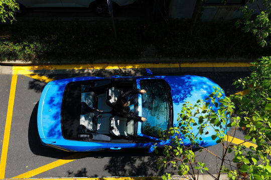 A stylish Asian girl sleeps inside a blue convertible.