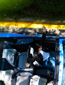 A stylish Asian girl sleeps inside a blue convertible.
